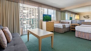 Una habitación de hotel con sofá, dos camas, escritorio, cómoda y una ventana grande con cortinas.