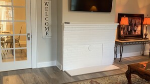 Una sala de estar con chimenea, televisor montado y un cartel que dice 'WELCOME'.