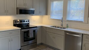 Una cocina moderna con electrodomésticos de acero inoxidable, armarios de colores claros y suelo de madera.