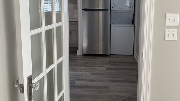 Puerta abierta que da a una cocina con refrigerador de acero inoxidable y microondas.