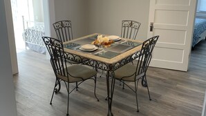 Un comedor con una mesa de vidrio, cuatro sillas y una araña.