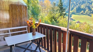 A wooden deck with a table and a vase of flowers. - Beautiful mountain views from the studio. Gondola lift at 500 m.  Free shuttle bus  (Le Grand-Bornand)