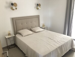A neatly made bed with a tufted headboard, two bedside tables with lamps, and a wall-mounted light fixture. - Detached, air-conditioned villa. Swimming pool. A garden with trees. Near the beaches (San-Gavino-Di-Carbini)