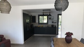 Eine moderne Küche mit dunklen Schränken, einem Holztisch und einem Blumenstrauß.