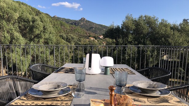 Ein Tisch für zwei Personen, gedeckt mit Tellern, Gläsern, einer Käseplatte und einer Weinflasche, mit Blick auf eine Berglandschaft.