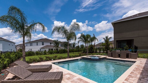 A rectangular swimming pool with a hot tub, surrounded by a brick deck and wicker lounge chairs. - Disney Dreams Luxury Home with Private Water Park (Kissimmee)