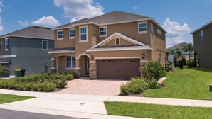 A two-story house with a garage, a front entrance, and a well-maintained lawn. - Disney Dreams Luxury Home with Private Water Park (Kissimmee)