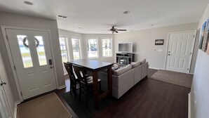 A modern kitchen with a dining area, a built-in TV, and a ceiling fan. - Waterfront Lake House - Portage Lake - 4 Beds, 3 Baths, Private Dock, Kayaks (Onekama)
