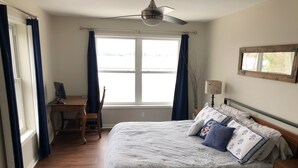 A bedroom with a bed, a desk, a chair, a lamp, and a window with curtains. - Waterfront Lake House - Portage Lake - 4 Beds, 3 Baths, Private Dock, Kayaks (Onekama)