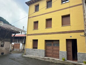 A yellow building with two ground-level windows and a brown door, a stone base, and a number '4' sign.