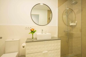 Ein modernes Badezimmer mit Toilette, Waschbecken mit Spiegel darüber und einer Duschkabine.