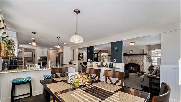 A modern kitchen with a central island, dining area with a wooden table and chairs, and a living area with a fireplace. - Colorado Mountain Getaway Retreat (Idaho Springs)