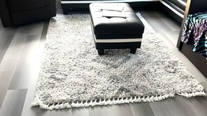 Una sala de estar moderna con un sofá modular, un sillón reclinable y una alfombra mullida sobre piso de madera.