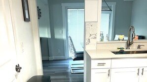 Una cocina moderna con armarios blancos, un lavamanos de acero inoxidable y un cesto de basura.