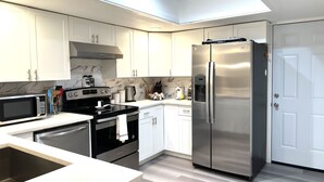 Una cocina moderna con armarios blancos, electrodomésticos de acero inoxidable y un tragaluz.