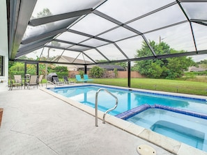 Une piscine extérieure couverte avec un espace patio, des chaises et une table.