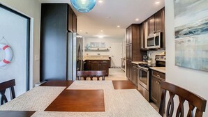 A modern kitchen with dark wood cabinets, stainless steel appliances, and a blue pendant light. - Beautiful Cozy 3-bedroom House (Naples)