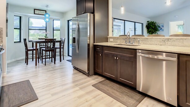 A modern kitchen with stainless steel appliances, a marble countertop, and a dining area with wooden chairs. - Beautiful Cozy 3-bedroom House (Naples)