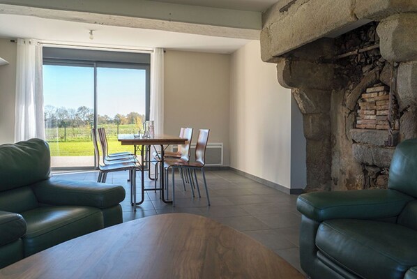 A spacious living area with a dining table and chairs, a fireplace, and a view of the outdoors.