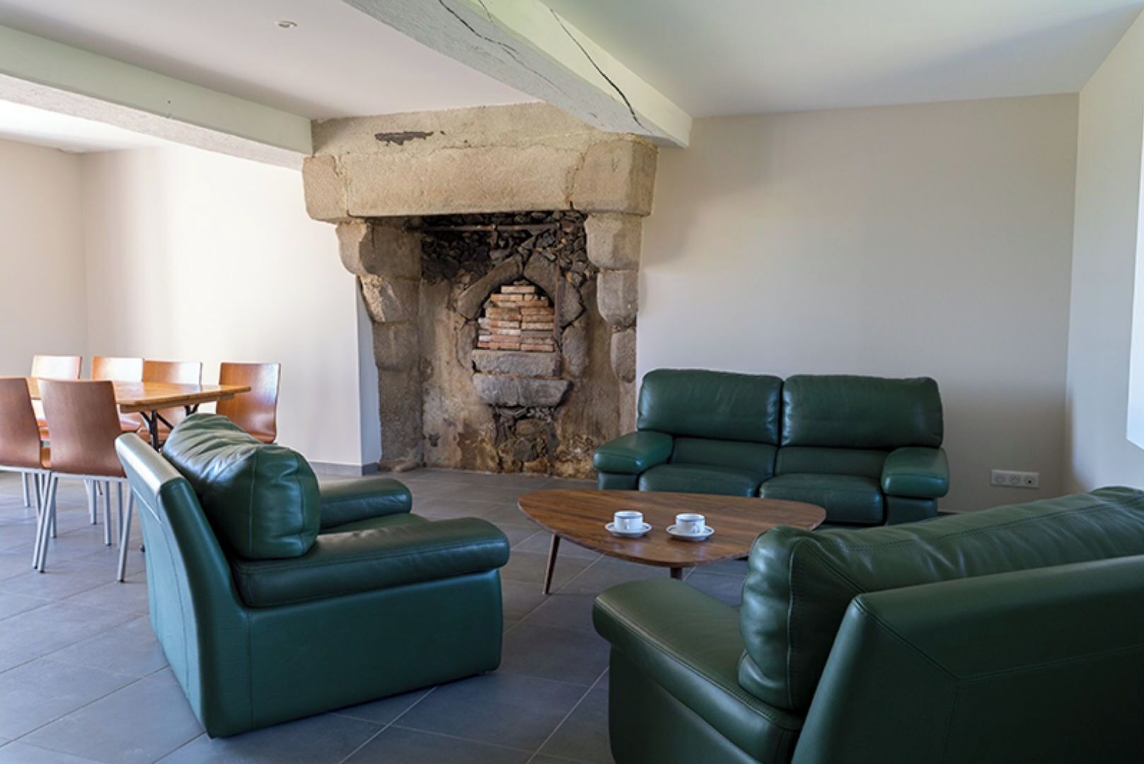 A living room with green leather sofas, a wooden coffee table, and a stone fireplace.