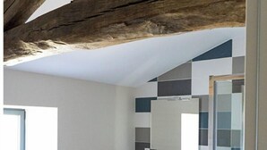 Un baño con techo de madera, pared de azulejos, lavamanos y mampara de cristal para la ducha.