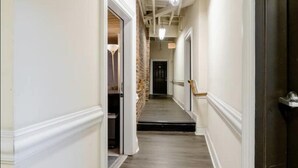 A hallway with a wooden floor, white walls, and a brick accent wall. - Industrial Chic Loft in the Heart of Downtown Richmond! (Richmond)
