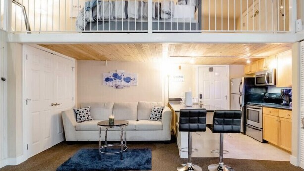 A two-story apartment with a living room, sofa, coffee table, and a kitchenette. - Industrial Chic Loft in the Heart of Downtown Richmond! (Richmond)