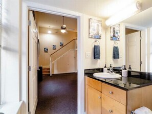 Bathroom features a large vanity with a sink and mirror, along with a towel rack.