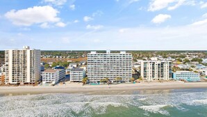 Ein Hotel direkt am Strand mit mehreren Gebäuden, einem Sandstrand und Wellen.