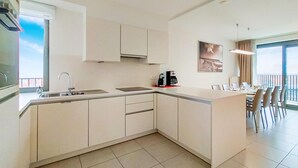 Eine moderne Küche mit einer großen Kochinsel, einem Essbereich mit Blick und einem Balkon.