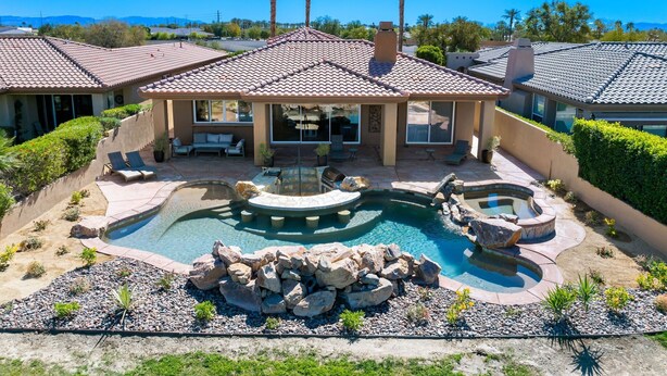 A house with a swimming pool, patio furniture, and a landscaped garden.