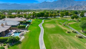 A golf course with a well-maintained fairway, a putting green, and a clubhouse with a swimming pool.