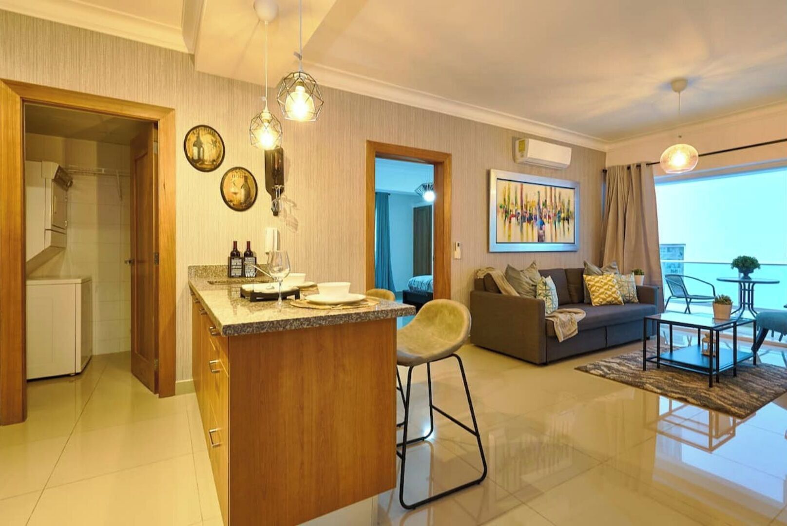 Uma sala de estar moderna com sofá, área de jantar com balcão e varanda com mesa e cadeiras.