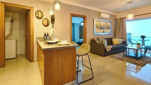 A modern living room with a sofa, a dining area with a bar, and a balcony with a table and chairs. - Modern & Cozy place w/pool & Parking in Downtown (Santo Domingo)