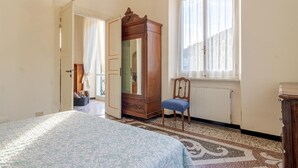 A bedroom with a bed, a wardrobe, a chair, and a window with curtains. - 3 bedroom pet friendly home in Zoagli (Zoagli)