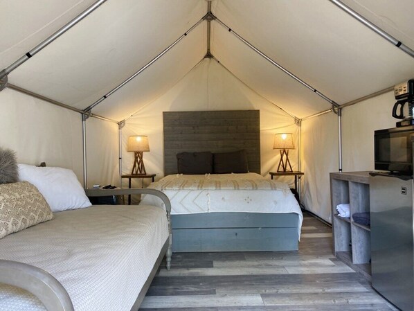 Alojamiento con carpa que incluye una cama, lámparas de noche, una kitchenette pequeña y un televisor.