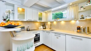 A modern kitchen with white cabinets, a built-in oven, and a window with a view of greenery.