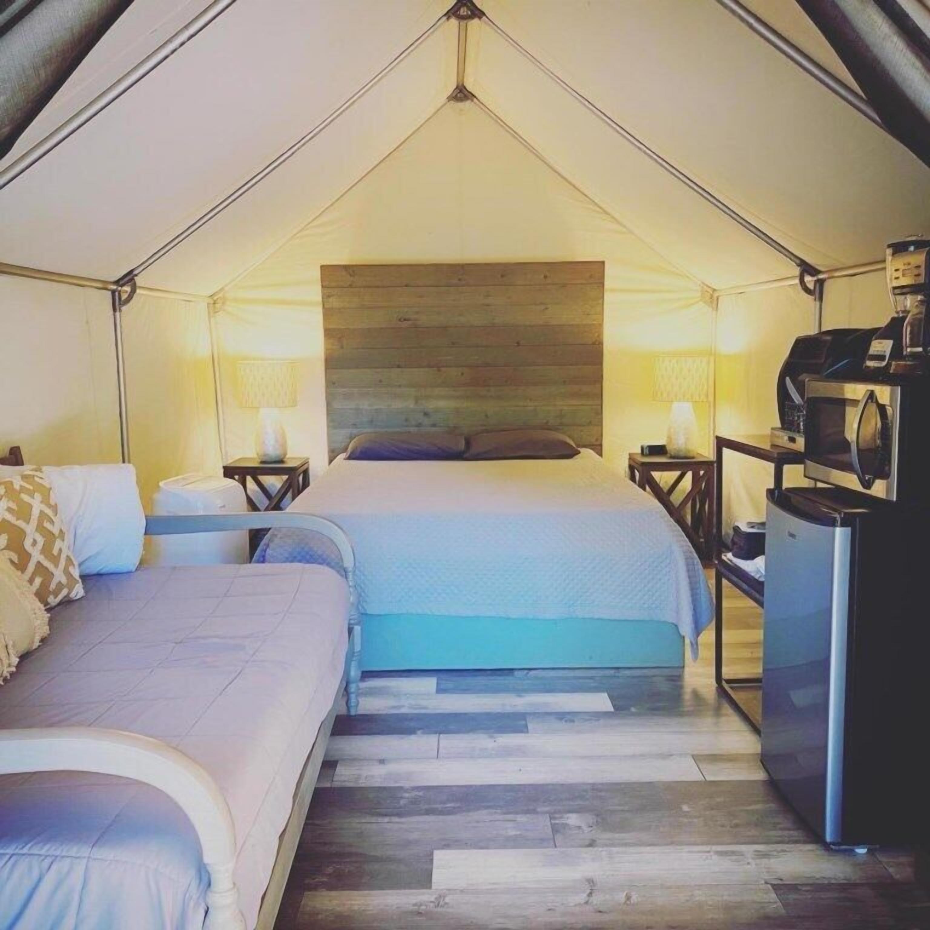A tent-style room with two beds, a coffee machine, and a refrigerator.