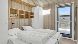 A bedroom with a bed, a wardrobe, and a door leading to a balcony.