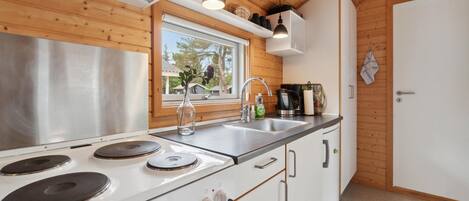 Una cocina moderna con estufa de acero inoxidable, un lavamanos y armarios de madera.