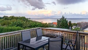 A balcony with a table and chairs overlooking a coastal view.
