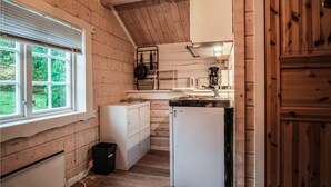 Cocina compacta con paredes de madera, una ventana y electrodomésticos básicos.
