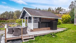 Una cabaña de troncos con porche y zona de estar al aire libre.