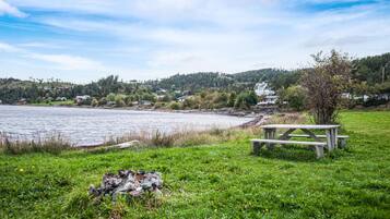 A lakeside picnic area with a wooden bench and a fire pit.