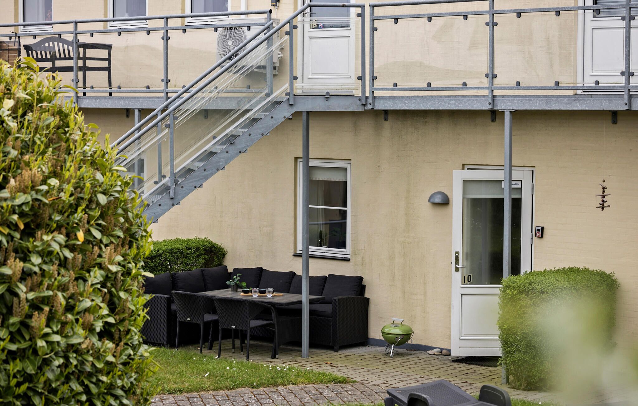Een terras met buitenmeubilair, een barbecue en een trap naar een hoger gelegen niveau.