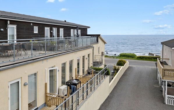 A seaside building with a balcony, a small outdoor seating area, and a view of the ocean. - Amazing apartment in Allinge with WiFi (Allinge)