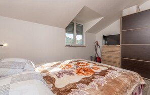 A bedroom with a bed, a window, a wardrobe, and a desk.