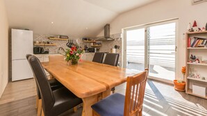 A modern kitchen with a dining area, featuring a wooden table, black chairs, and a vase of flowers. - Gorgeous apartment in Banjevci (Banjevci)