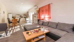 A modern living room with a grey sofa, wooden coffee table, and a dining area with a table and chairs. - Gorgeous apartment in Banjevci (Banjevci)