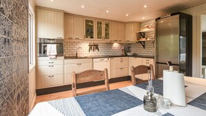 A modern kitchen with light wood cabinets, a stainless steel refrigerator, and a wooden dining table with chairs. - 2 bedroom awesome home in Brastad (Brastad)